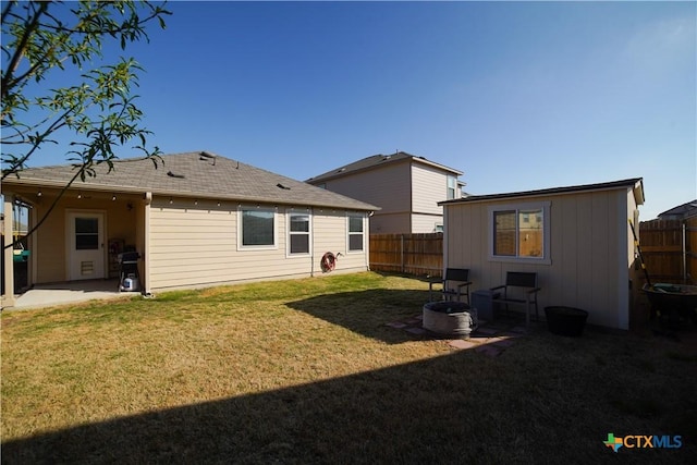 back of property featuring a yard, roof with shingles, a fenced backyard, and a patio area