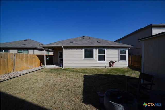 back of house featuring a yard, a fenced backyard, and a shingled roof