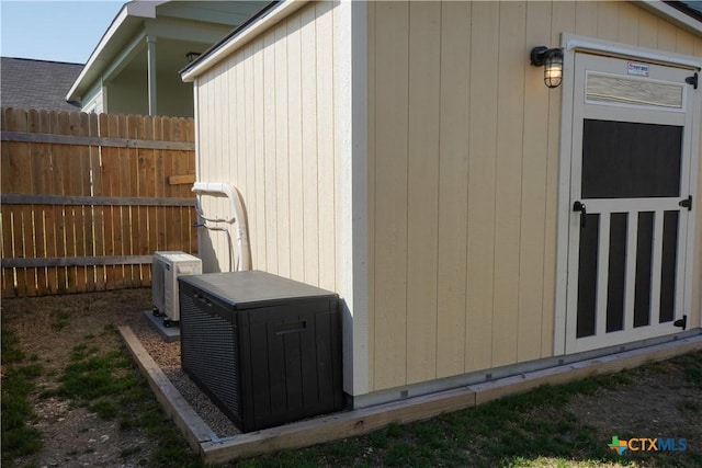 view of outbuilding featuring ac unit and fence