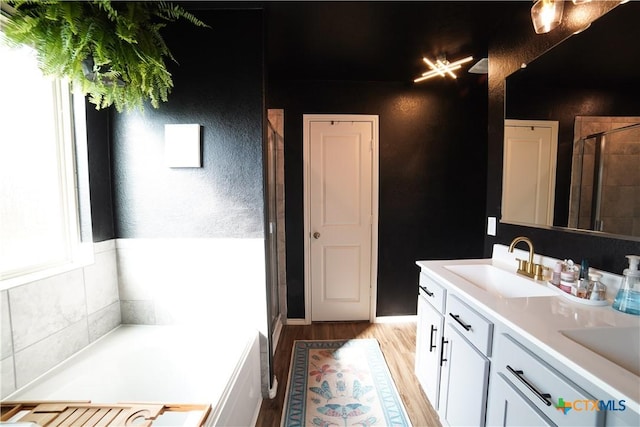 full bath with wood finished floors, double vanity, a sink, a shower stall, and a bath