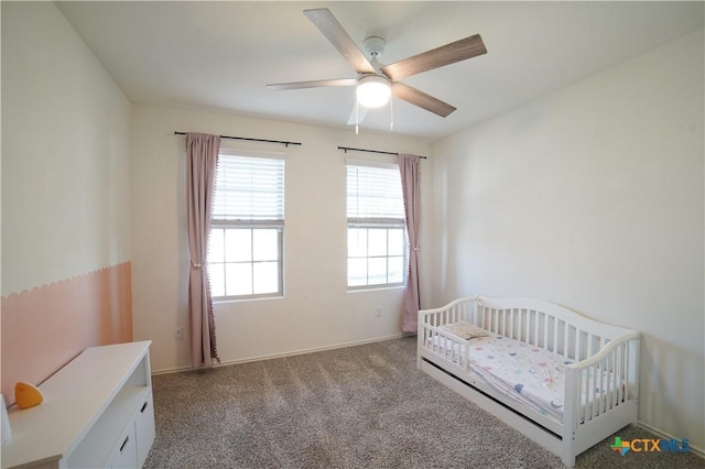 bedroom featuring a nursery area, a ceiling fan, and carpet