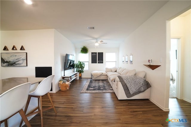 living area with visible vents, dark wood-type flooring, baseboards, vaulted ceiling, and a ceiling fan