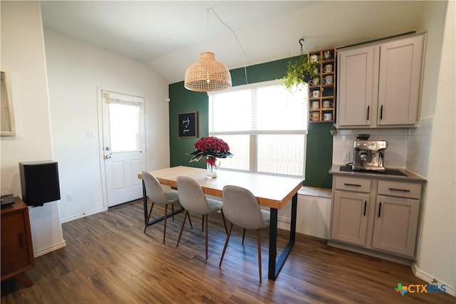 dining space with baseboards, plenty of natural light, dark wood finished floors, and vaulted ceiling