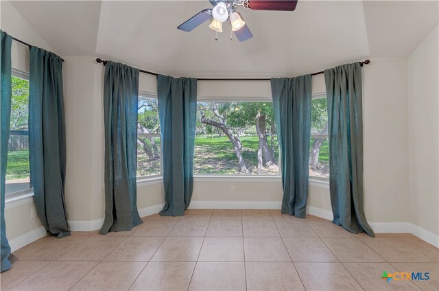 tiled spare room with vaulted ceiling and ceiling fan