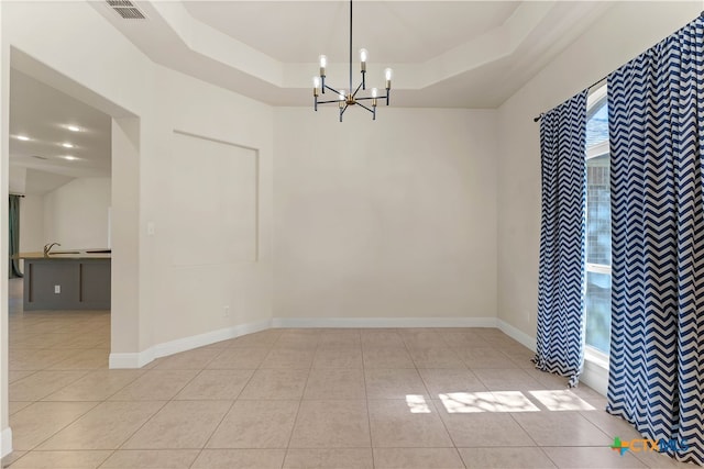 unfurnished dining area featuring light tile patterned flooring, a notable chandelier, and a tray ceiling