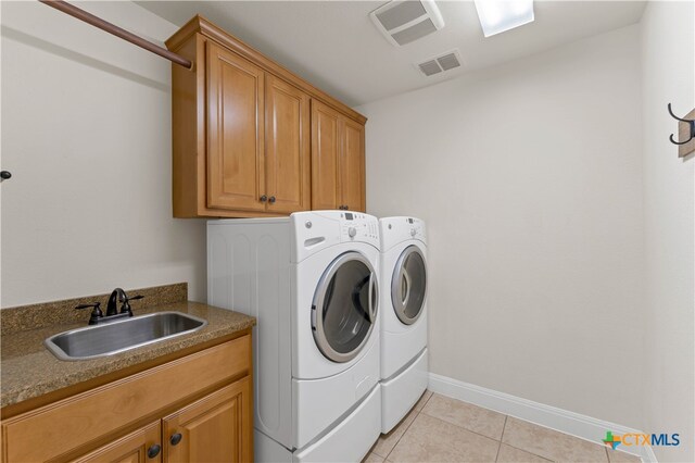 laundry area featuring cabinets, washing machine and dryer, light tile patterned floors, and sink