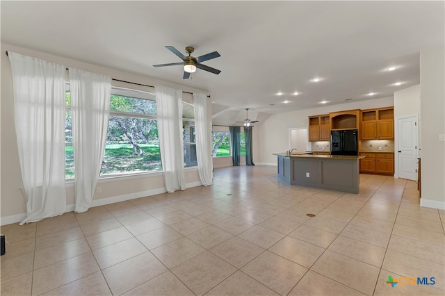 kitchen featuring a kitchen island with sink, black refrigerator with ice dispenser, ceiling fan, and light tile patterned floors