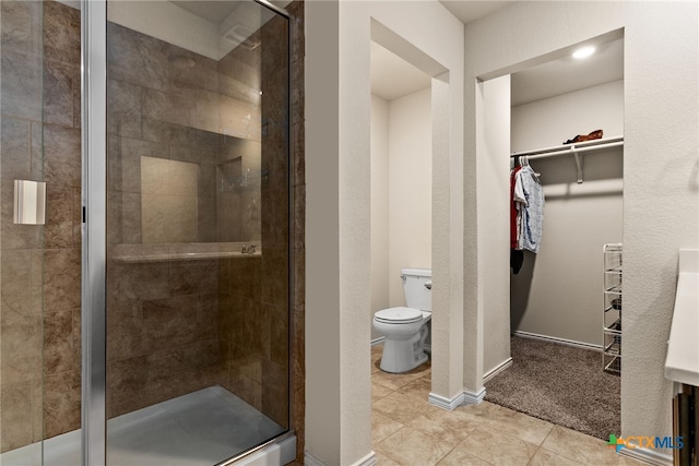 bathroom featuring toilet, a shower with shower door, and tile patterned flooring