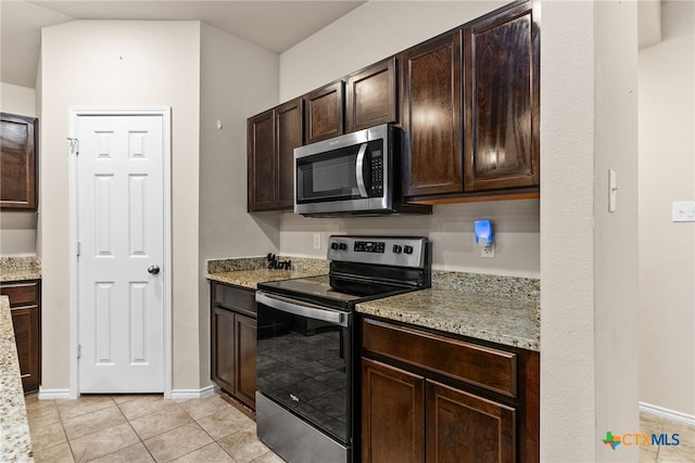 kitchen with appliances with stainless steel finishes, light stone countertops, dark brown cabinets, and light tile patterned floors