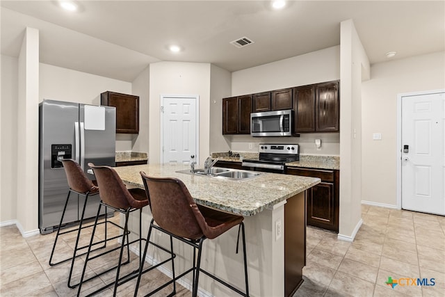 kitchen with appliances with stainless steel finishes, sink, a breakfast bar area, dark brown cabinetry, and a center island with sink