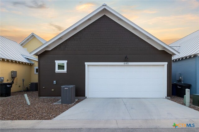 645 Center Grn, New Braunfels, TX 78130 - property exterior at dusk featuring central AC unit, an attached garage, an outbuilding, and driveway