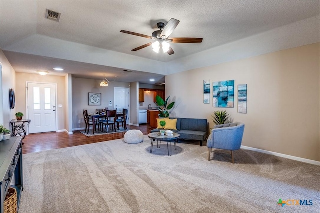 living area featuring visible vents, baseboards, a textured ceiling, and carpet