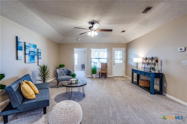 living area with visible vents, baseboards, carpet, lofted ceiling, and a ceiling fan