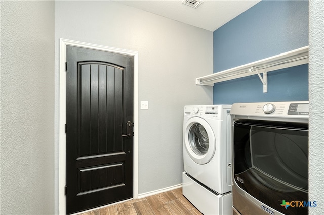 clothes washing area with light hardwood / wood-style flooring and washer and dryer