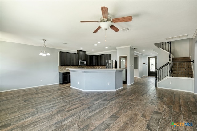 kitchen featuring tasteful backsplash, ornamental molding, appliances with stainless steel finishes, dark hardwood / wood-style flooring, and a center island