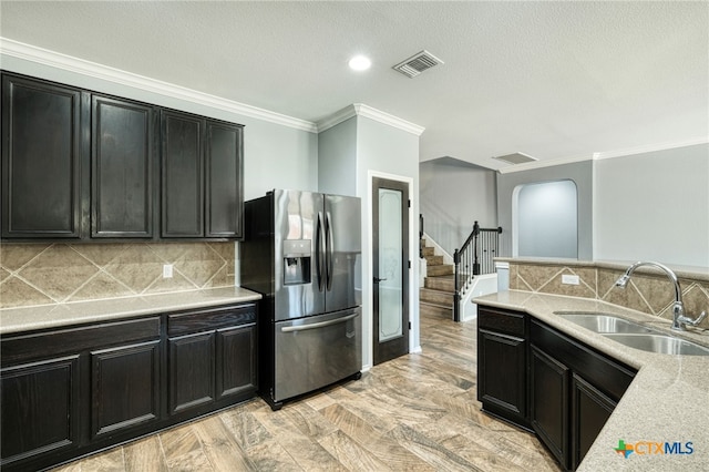 kitchen featuring tasteful backsplash, ornamental molding, stainless steel fridge, light wood-type flooring, and sink