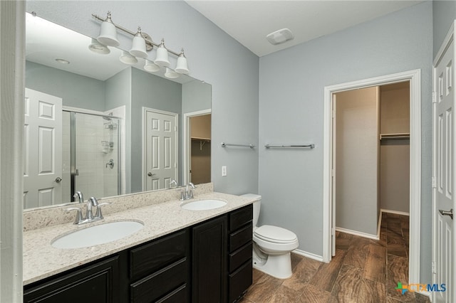 bathroom with toilet, vanity, hardwood / wood-style floors, and a shower with door