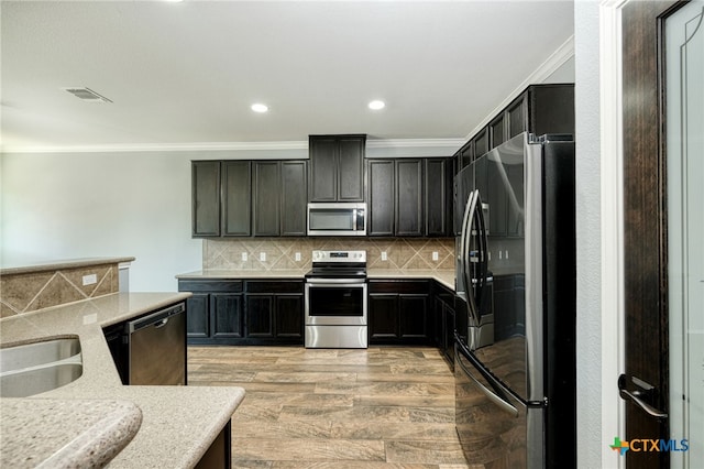 kitchen with sink, appliances with stainless steel finishes, backsplash, crown molding, and light wood-type flooring