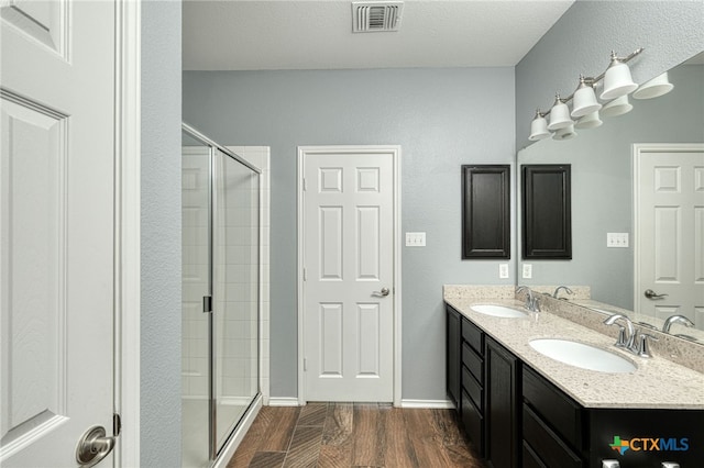 bathroom with hardwood / wood-style flooring, vanity, a textured ceiling, and walk in shower