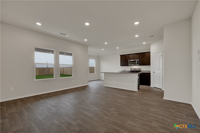 interior space with dark brown cabinetry, appliances with stainless steel finishes, dark hardwood / wood-style flooring, and a kitchen island with sink