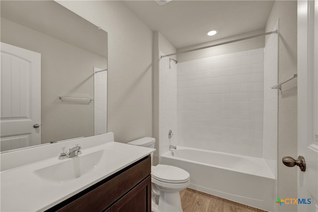 full bathroom featuring hardwood / wood-style flooring, vanity, tiled shower / bath combo, and toilet