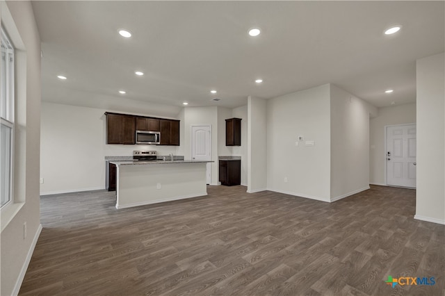 kitchen with a kitchen island with sink, dark brown cabinets, dark hardwood / wood-style flooring, and appliances with stainless steel finishes