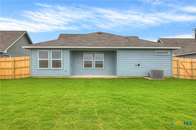 rear view of property featuring cooling unit and a lawn