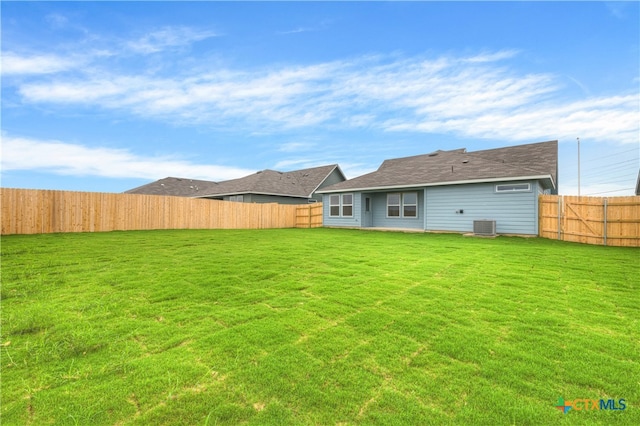 rear view of house featuring central AC and a yard