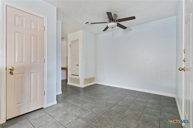 tiled spare room featuring a ceiling fan, visible vents, and baseboards