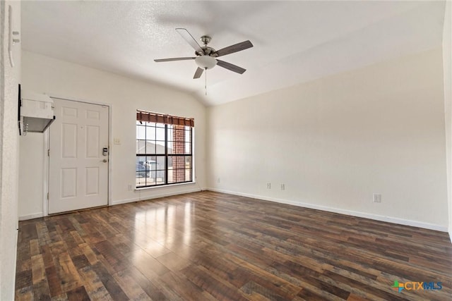 spare room featuring baseboards, dark wood-style flooring, a ceiling fan, and vaulted ceiling