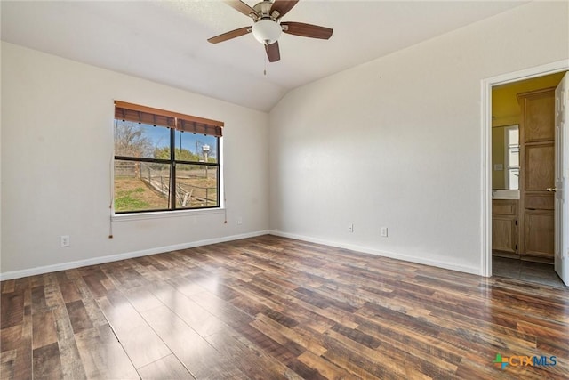 spare room featuring baseboards, lofted ceiling, dark wood finished floors, and a ceiling fan