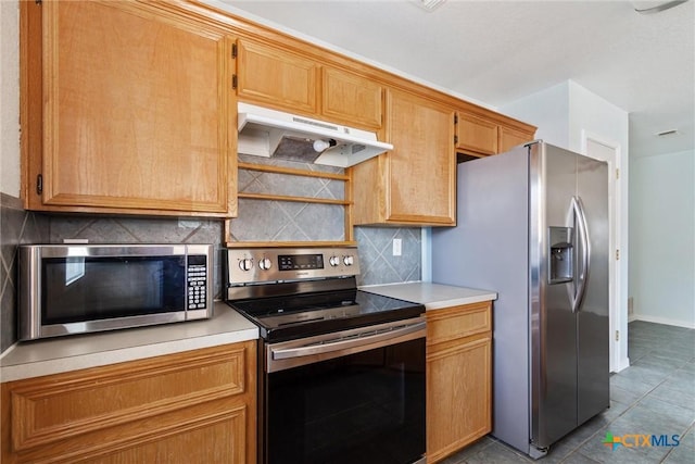 kitchen with under cabinet range hood, tasteful backsplash, appliances with stainless steel finishes, tile patterned flooring, and light countertops