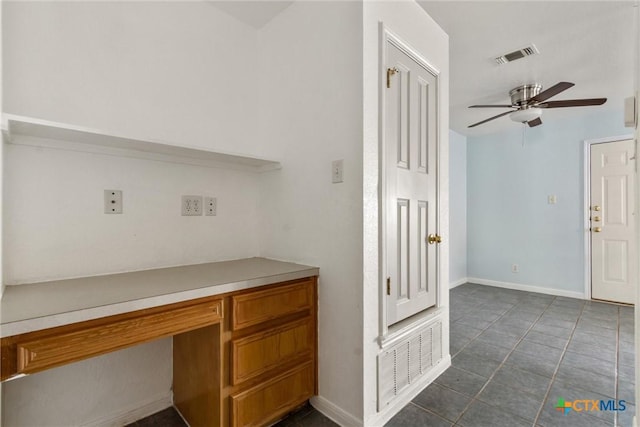 unfurnished office featuring built in desk, visible vents, baseboards, and ceiling fan