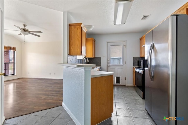 kitchen featuring visible vents, a peninsula, light tile patterned flooring, stainless steel appliances, and a ceiling fan