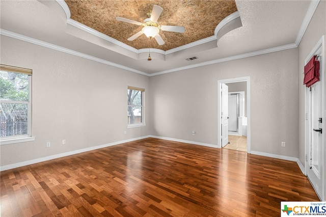 unfurnished bedroom featuring crown molding, ceiling fan, connected bathroom, a tray ceiling, and wood-type flooring