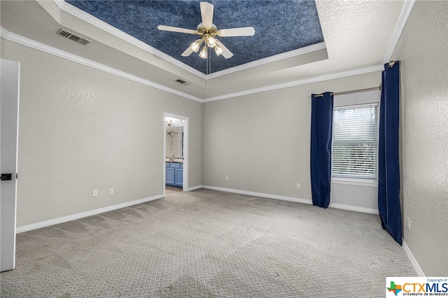 empty room featuring carpet flooring, ceiling fan, a raised ceiling, and ornamental molding