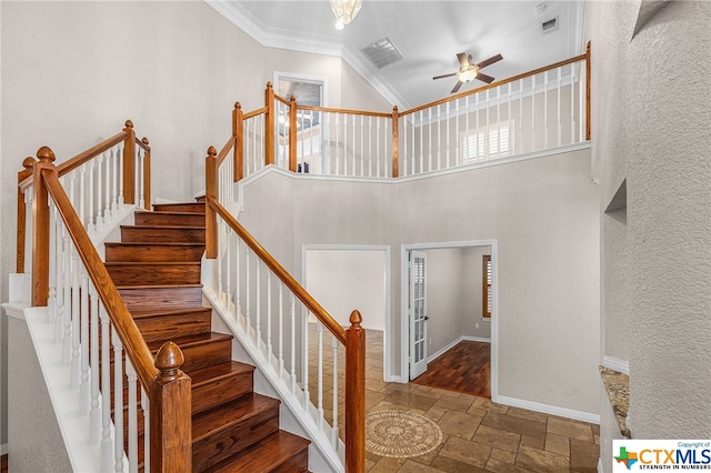 stairs featuring ceiling fan with notable chandelier, a towering ceiling, and crown molding