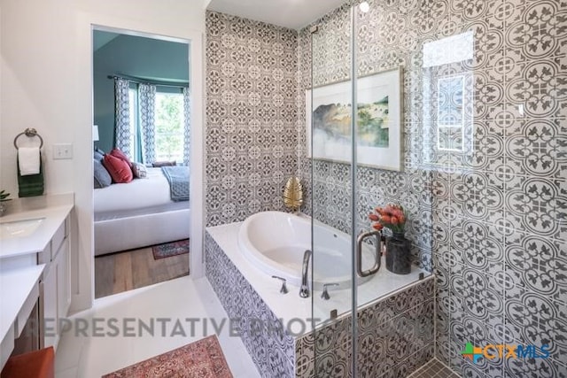 ensuite bathroom featuring vanity, a garden tub, and tiled shower