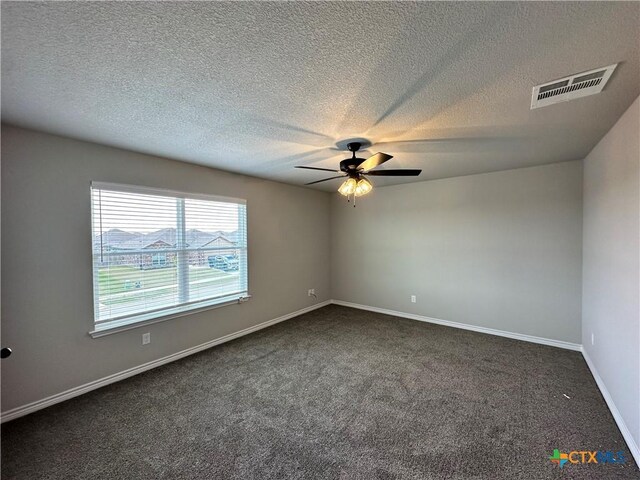 spare room featuring baseboards, a ceiling fan, dark colored carpet, and visible vents