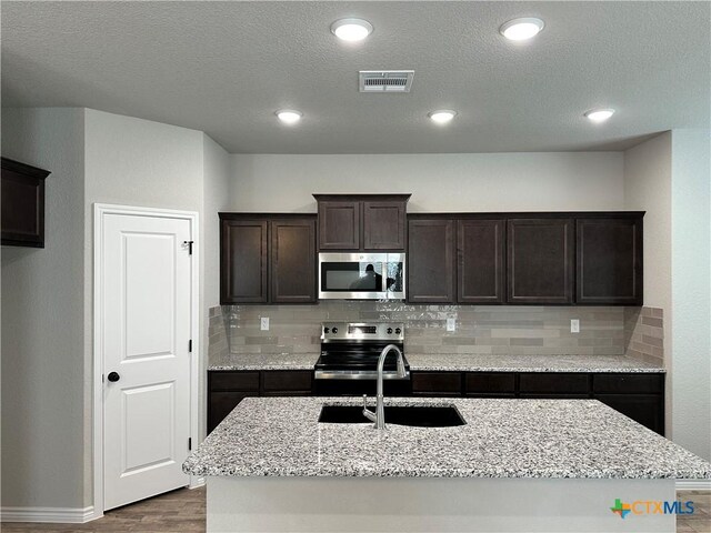 3005 Hedwig St, Killeen, TX 76549 - kitchen with stainless steel appliances, a sink, wood finished floors, tasteful backsplash, and dark brown cabinets