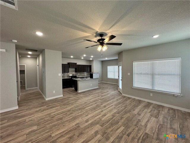 unfurnished living room featuring baseboards, a ceiling fan, wood finished floors, and a textured ceiling