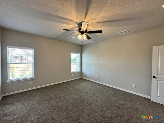 empty room with dark colored carpet, visible vents, and ceiling fan