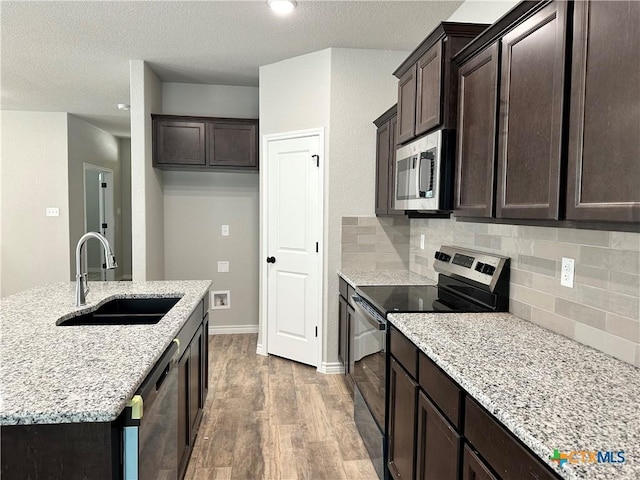 3005 Hedwig St, Killeen, TX 76549 - kitchen featuring stainless steel appliances, a sink, wood finished floors, tasteful backsplash, and dark brown cabinets