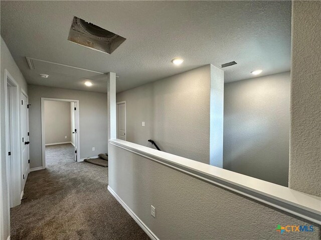 corridor with attic access, baseboards, an upstairs landing, a textured wall, and carpet floors