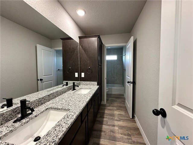 bathroom with wood finished floors, a sink, a textured ceiling, and toilet