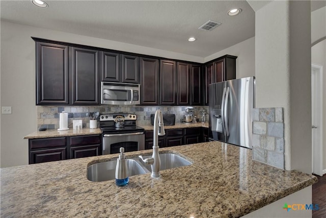 6333 Iris Run, New Braunfels, TX 78132 - kitchen with stainless steel appliances, light stone counters, backsplash, wood finished floors, and recessed lighting