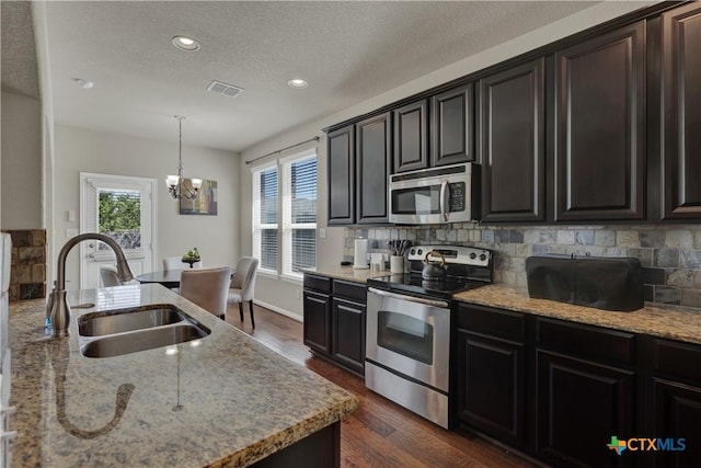 6333 Iris Run, New Braunfels, TX 78132 - kitchen featuring stainless steel appliances, a chandelier, decorative backsplash, dark wood-style flooring, and light stone countertops