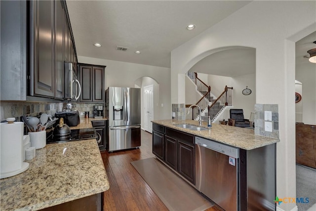 6333 Iris Run, New Braunfels, TX 78132 - kitchen with stainless steel appliances, arched walkways, light stone counters, dark brown cabinets, and dark wood-style flooring