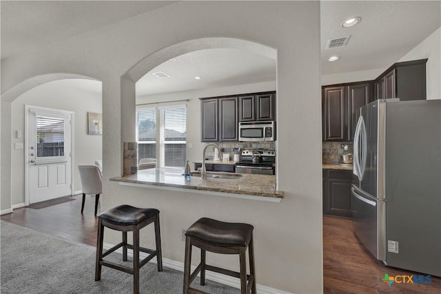 6333 Iris Run, New Braunfels, TX 78132 - kitchen featuring appliances with stainless steel finishes, a kitchen breakfast bar, decorative backsplash, arched walkways, and light stone counters