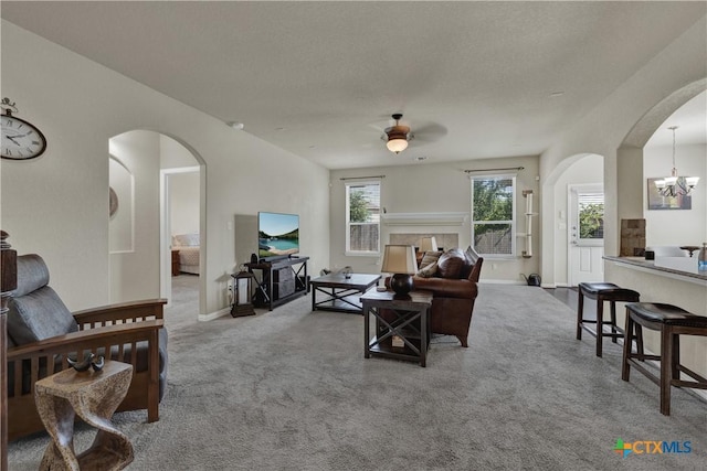 6333 Iris Run, New Braunfels, TX 78132 - carpeted living area featuring arched walkways, a ceiling fan, a chandelier, and a textured ceiling